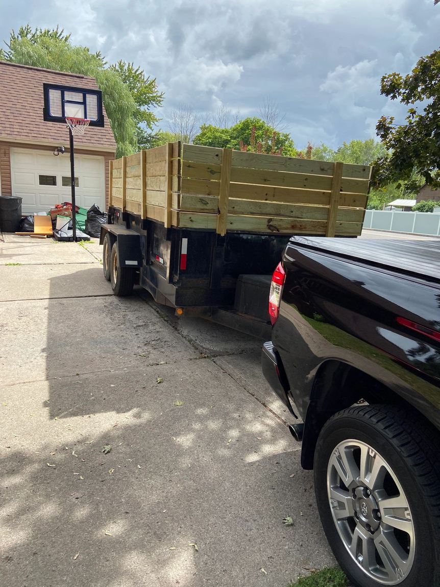 CNY Junk Hauling's truck and dump trailer parked in a residential driveway, ready to load a junk removal job